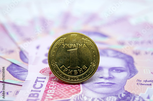 Obraz na płótnie The coin is one hryvnia against the background of paper banknotes of the Ukrainian currency. w salonie