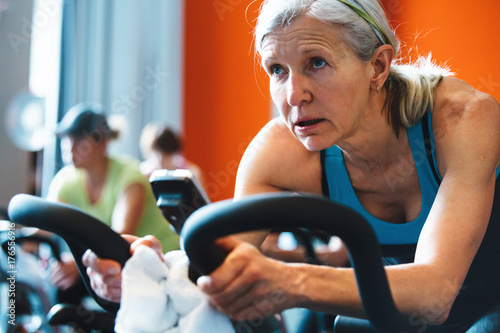 Older caucasian woman working hard during spin cycle class photo