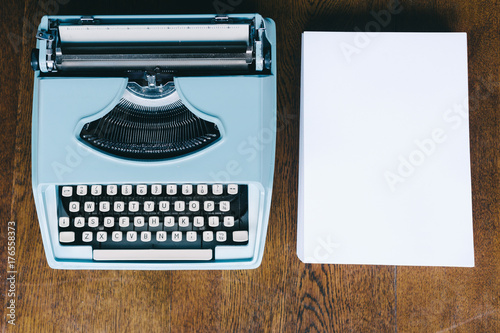 blue typewriter with a ream of blank paper