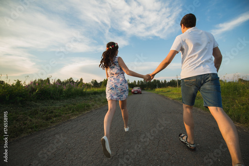 Young couple running along country road.