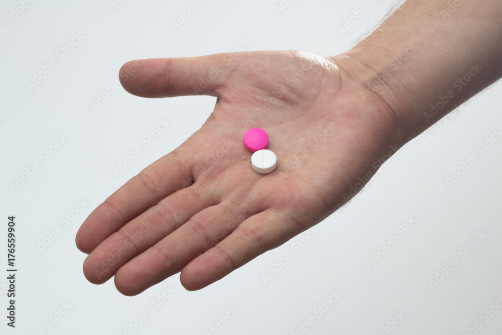 hand holding white and pink pills against white background hand holding white and pink pills against white background