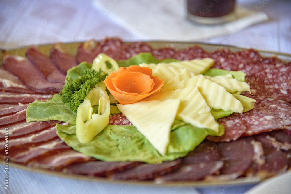 Typical Serbian appetizing food, slices of yellow cheese and sliced ham, salami and pork Typical Serbian appetizing food, slices of yellow cheese and sliced ham, salami and pork