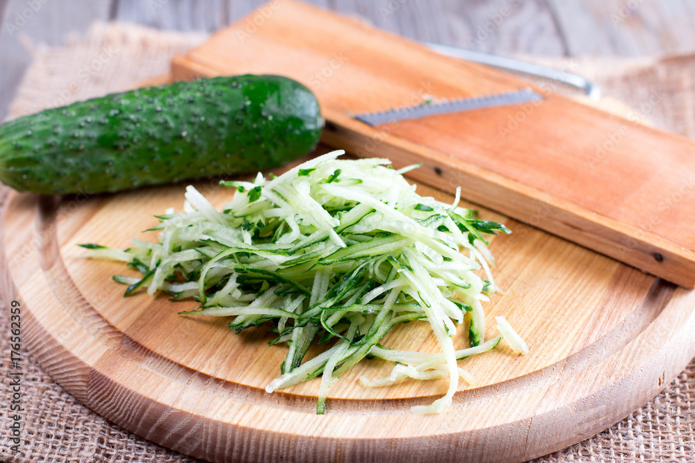 Green cucumber grated on wooden board