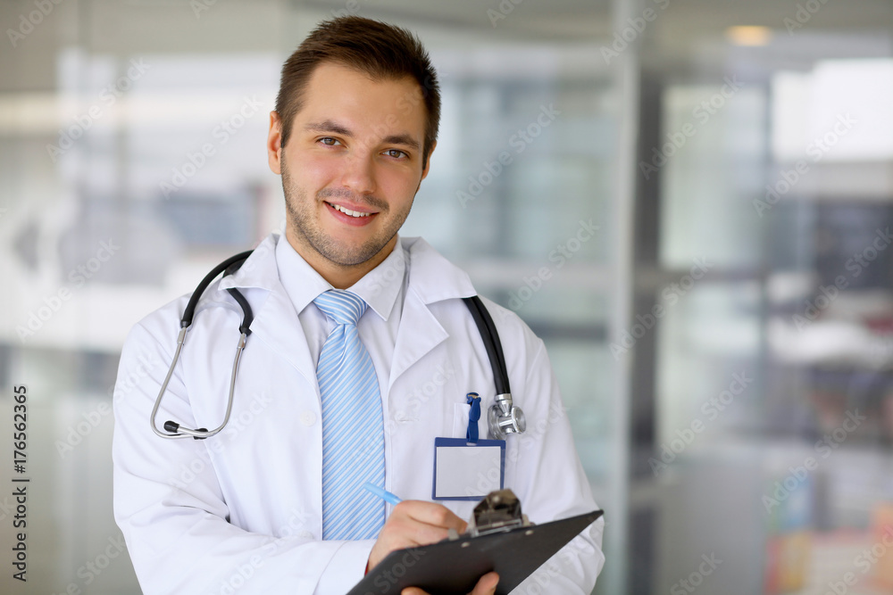Smiling doctor waiting for his team while standing upright Smiling doctor waiting for his team while standing upright