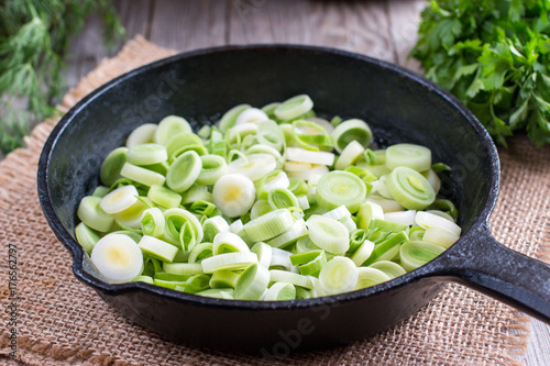 Stewing leek slices in a frying pan on a hot plate