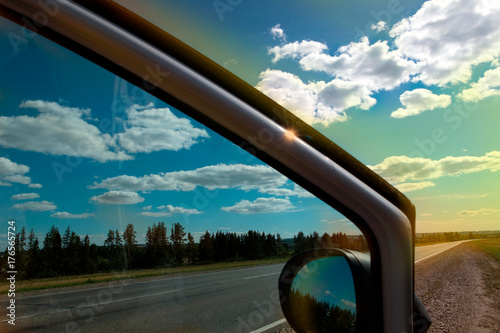 Car stop on the roadside.
Horizontally. Toning. The open door of the car stopped at the side of the highway. The sun shines through the tinted glass, clouds.