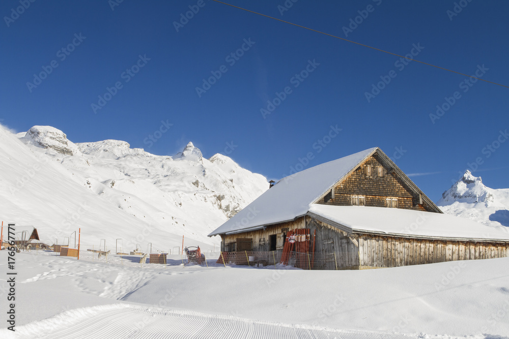 TIMBER FARMER BARN HOUSE IN WINTER MOUNTAIN SNOW COVERED LANDSCAPE IN MELCHSEE FRUTT, SWITZERLAND
