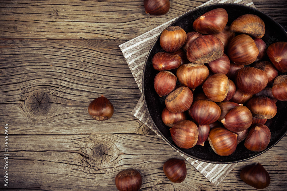 chestnuts in a pan on a wooden background chestnuts in a pan on a wooden background