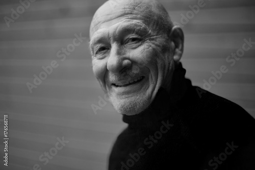 .Black and white horizontal capture of handsome happy senior expressing positivity and young soul, playing with camera and laughing. Old senior man closeup portrait. People, feelings, human concept.