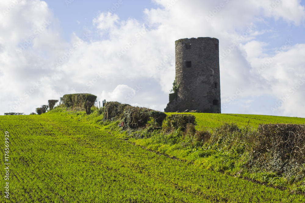 An old stone tower of unknown origin to the photographer on a hill top in a cut hay field on a farm near Kircubbin on the Ards Peninsula in Count down Northern Ireland 