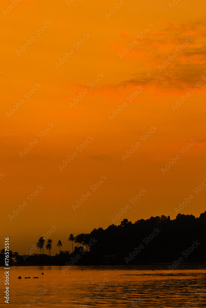 After sunset orange glow over the sun and sea, with silhouette of an island behind