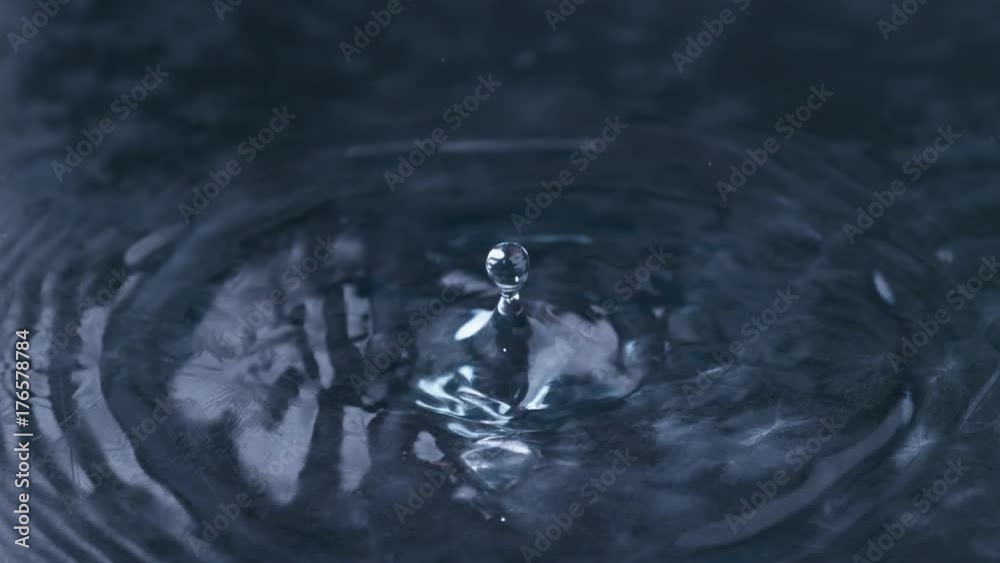 Droplet of clean fresh water falling and creating ripples, close up slow motion
