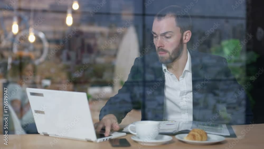 Young businessman working in cafe & making video call on laptop