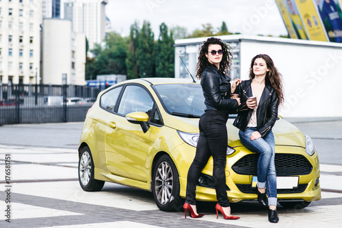 Two beautiful modern girls are standing by the car and having fun © speed300