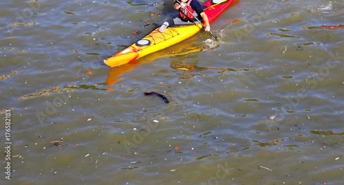 London, United Kingdom. SEPTEMBER 1, 2017: Kayaker paddling through polluted waterway.  Thames River, London, England	