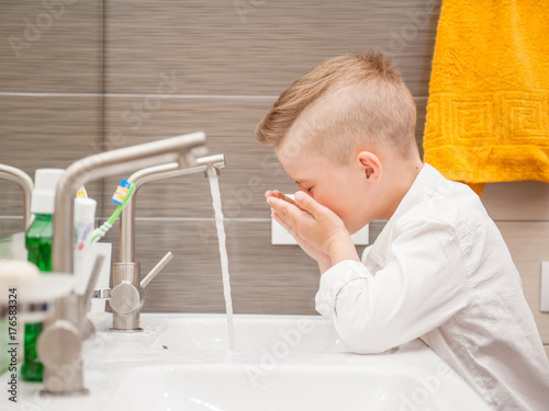 Boy is washing his face in the bathroom