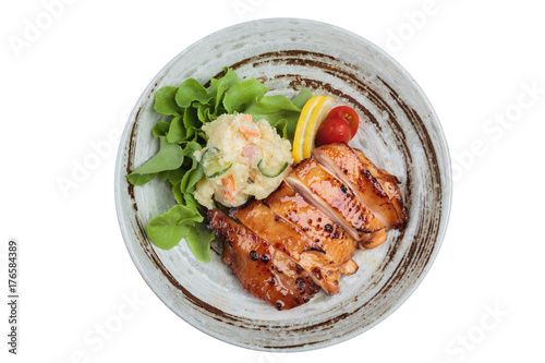 Isolated Top view of Teriyaki chicken served with potato salad, sliced lemon, totmato and green oak in round stone plate. photo