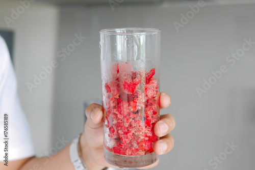 hand holding ice fresh raspberry in glass