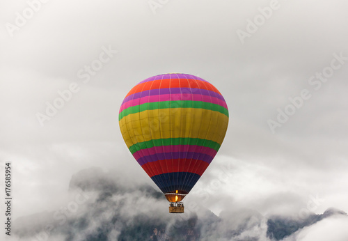 Colorful hot air balloon fly over the mountains in the morning with thick fog.