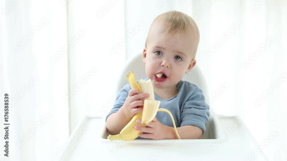 Attractive baby boy eats a banana white background Attractive baby boy eats a banana white background