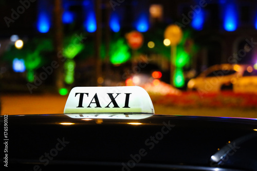 A glowing taxi sign on the roof of the car in the light of the lights of the night city.