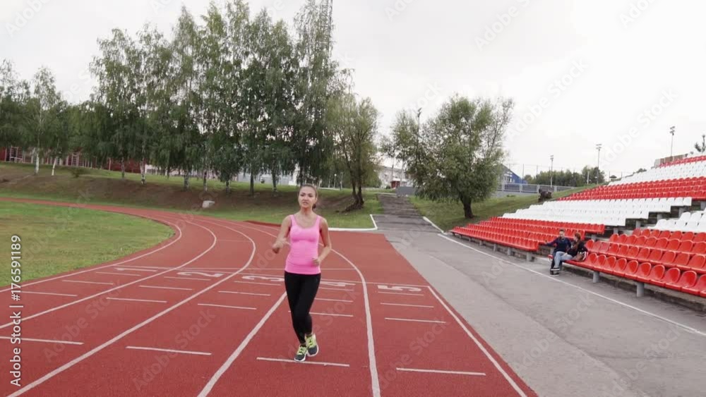 Girl runs around the stadium. Girl runs around the stadium.