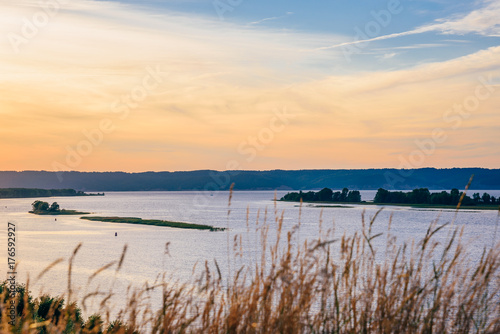 Grass against the river shore in the sunset light.