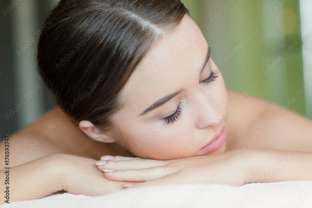 Relaxed girl with closed eyes lying in spa salon before bodycare procedure