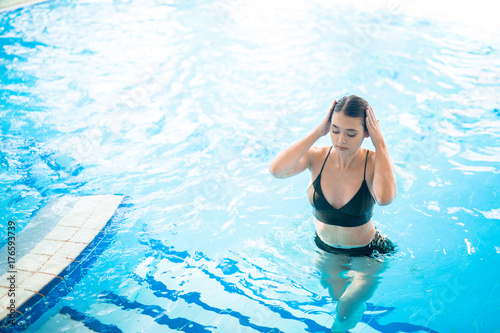 Young woman in bikini walking out of swimming-pool or spa jacuzzi