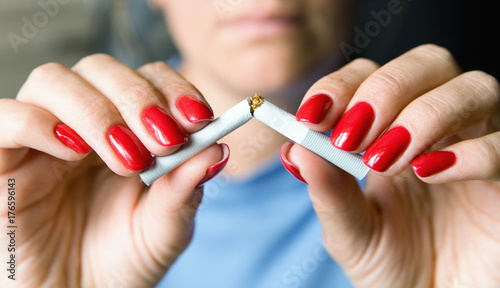 Obraz na plátně A girl with a beautiful manicure breaks a cigarette.