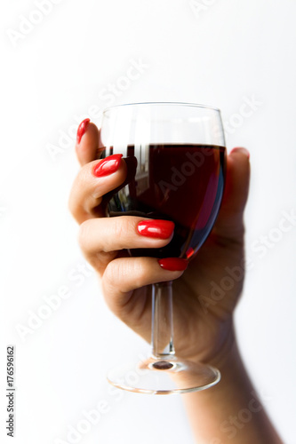 A glass of red wine in a beautiful woman's hand.