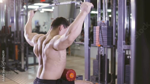 Young Man Bodybuilder Is Working On His back muscles With lat Machine