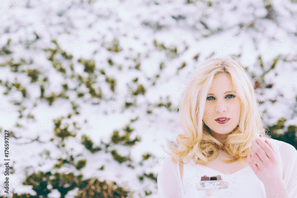 Blonde Frau isst Pralinen in Winterlandschaft Blonde Frau isst Pralinen in Winterlandschaft