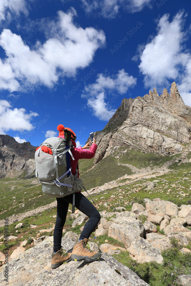 successful woman hiker use smartphone in mountain top rock