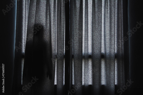 horror scene of woman's shadow standing hiding behind curtain