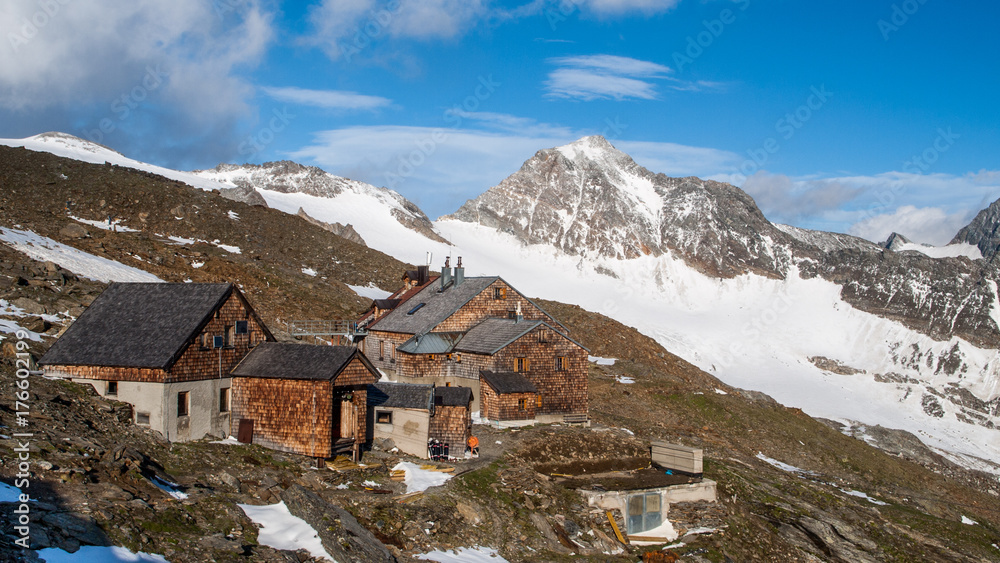 Landscape view of Defreggerhaus mountain hut, mountains covered with snow in the background. Spring, Grossvenediger, Hohe Tauern, Alps, Austria.
