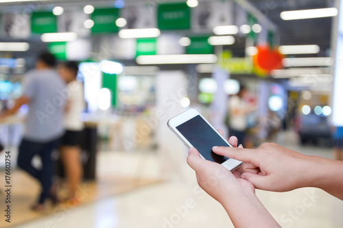 blurred photo and smartphone on people in shopping mall with bokeh.