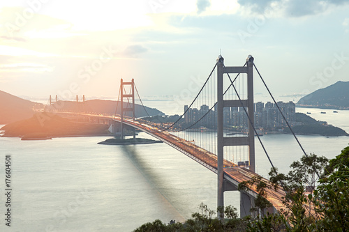 silhouette Tsing Ma double-decked suspension bridge between Ma Wan island and Tsing Yi island in Hong Kong, China at sunset and flare