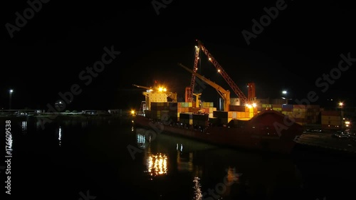 Unloading Cargo from a Ship in the Sea Port of Batumi by Night. Time Lapse. Cranes in seaport lift cargo containers on the ship and drop them to the pier. Full HD 1920 x 1080, 25 fps photo