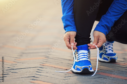 Young woman runner tying shoelace before run