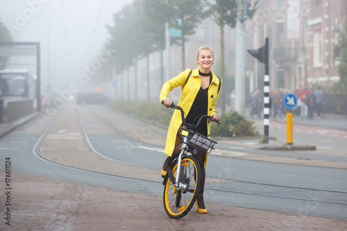 Young woman with bicycle in a misty city