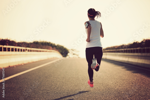 Young fitness sport woman running on city road