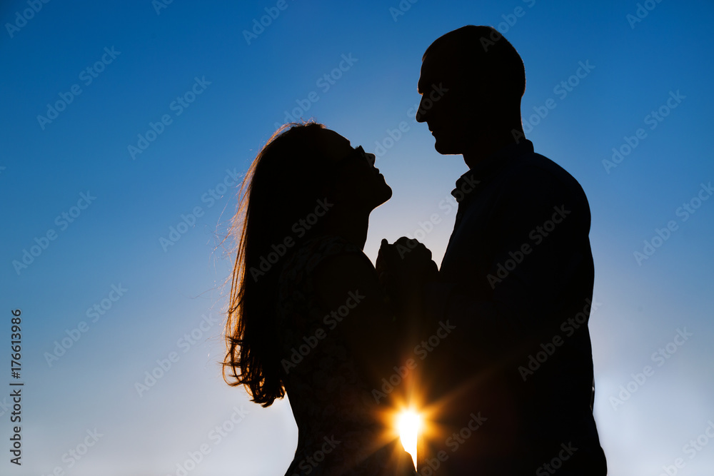 Silhouette of a loving couple on the background of the sunset