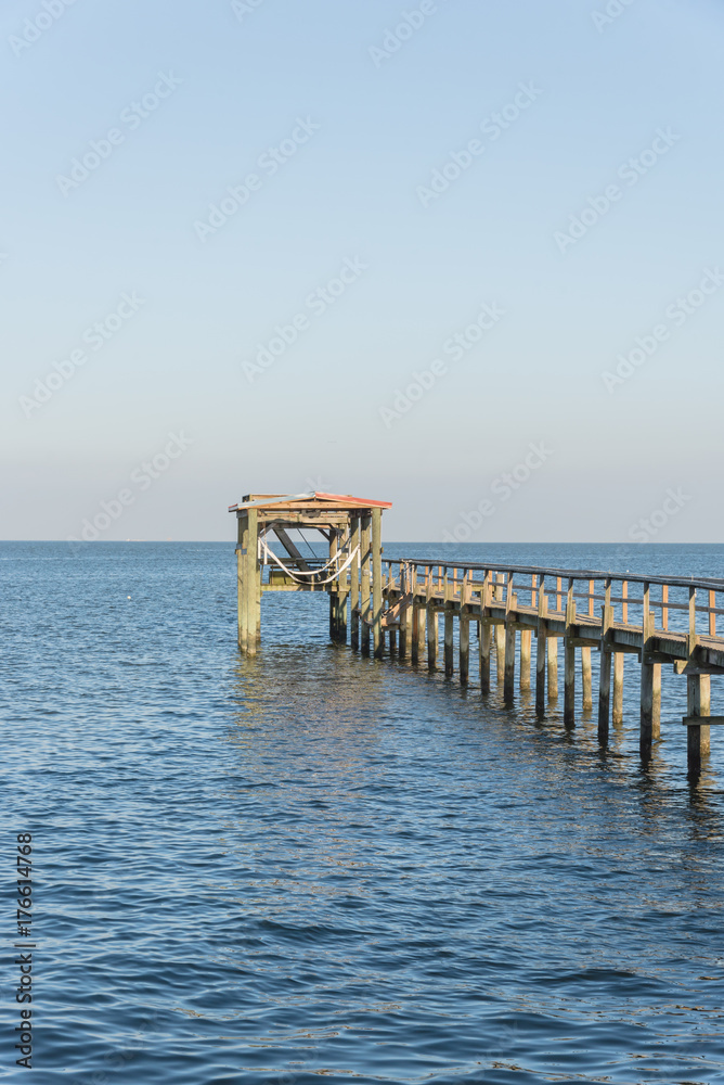 Wooden fishing piers stretching out over Galveston Bay in Kemah, Texas,  USA. Foot pier for saltwater fishing of vacation home/beach house  rental/bay home in Lighthouse District waterfront at sunset Stock Photo