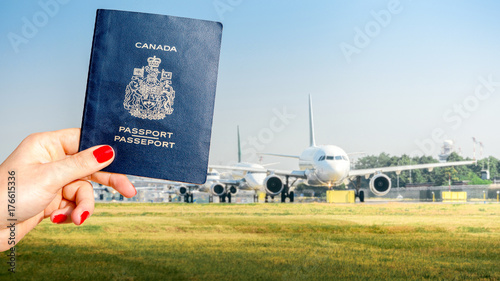 Digital composite of holding a Canadian passport with a row of commercial airplanes on taxiing on tarmac  - travel concept photo