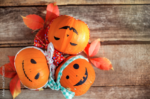 Three happy pumpkins with bandanas on wooden table. View from above, selective focus