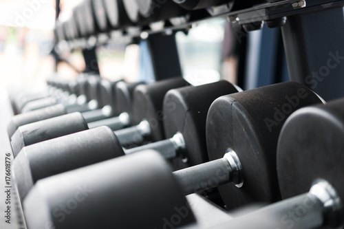 Row of dumbbells in gym. Black dumbbell set in sport fitness center.