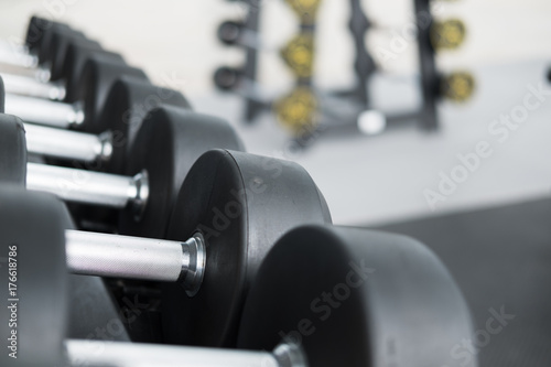 Row of dumbbells in gym. Black dumbbell set in sport fitness center.