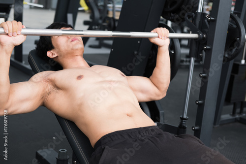 young man execute exercise with weightlifting machine in fitness center. male athlete pump up muscle in gym. sporty guy working out in health club.