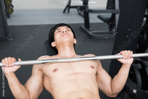 young man execute exercise with weightlifting machine in fitness center. male athlete pump up muscle in gym. sporty guy working out in health club.